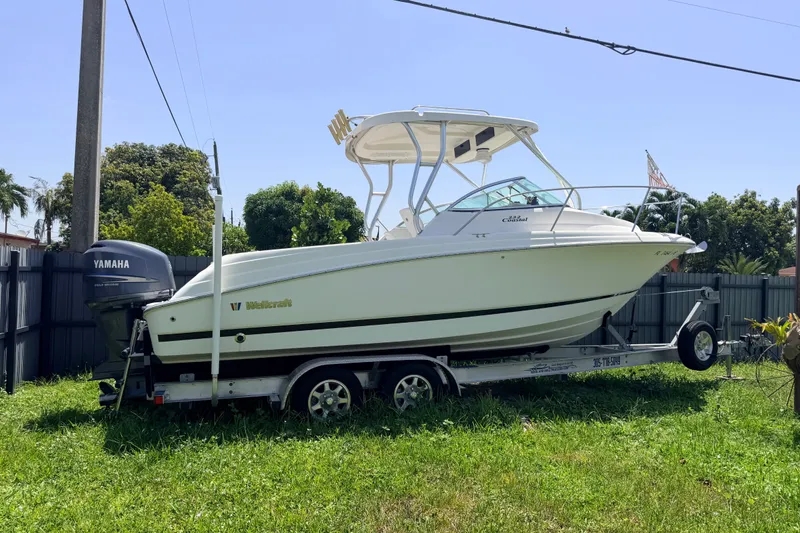 The Image of 2011 Wellcraft 232 Coastal boat on trailer with Yamaha outboard motor, parked on grass. - 0