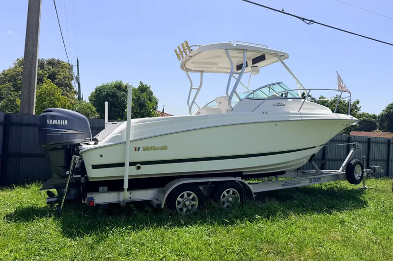 Slide: The Image of 2011 Wellcraft 232 Coastal boat on trailer with Yamaha outboard motor, parked on grass. - 24