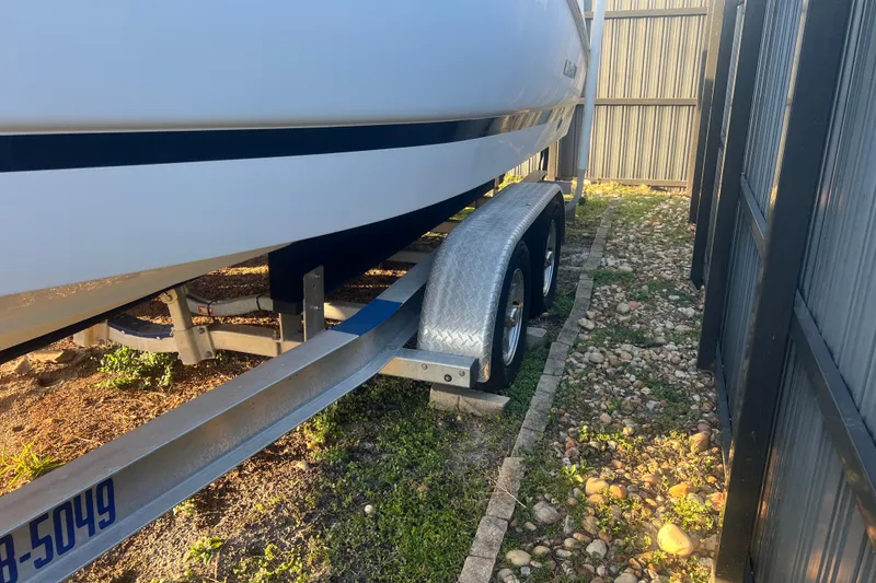 Slide: The Image of 2011 Wellcraft 232 Coastal boat on trailer, parked beside a metal fence. - 7