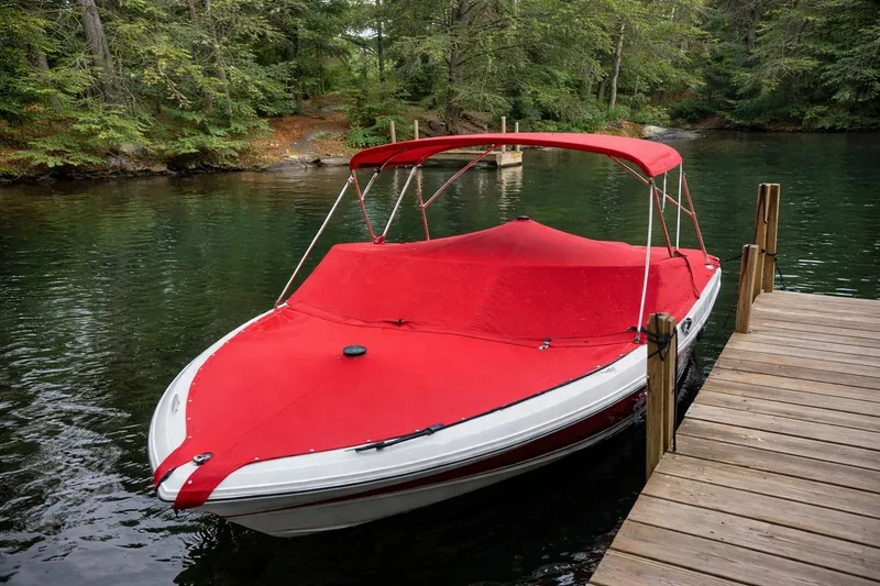Slide: The Image of 2020 Cobalt 200S boat with red cover docked on a serene lake. - 2