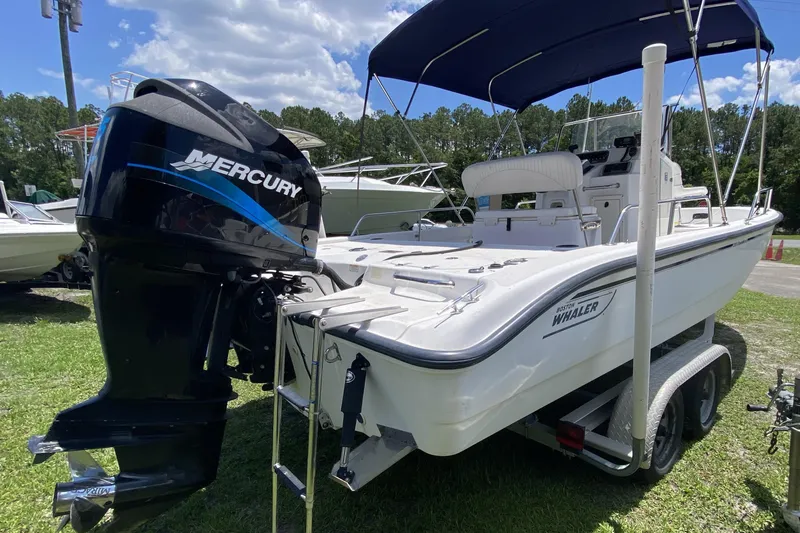 The Image of 2004 Boston Whaler 220 Dauntless boat with Mercury engine on trailer, parked outdoors. - 0