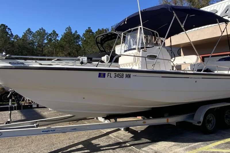 The Image of 2004 Boston Whaler 220 Dauntless boat on trailer, parked outdoors. - 1
