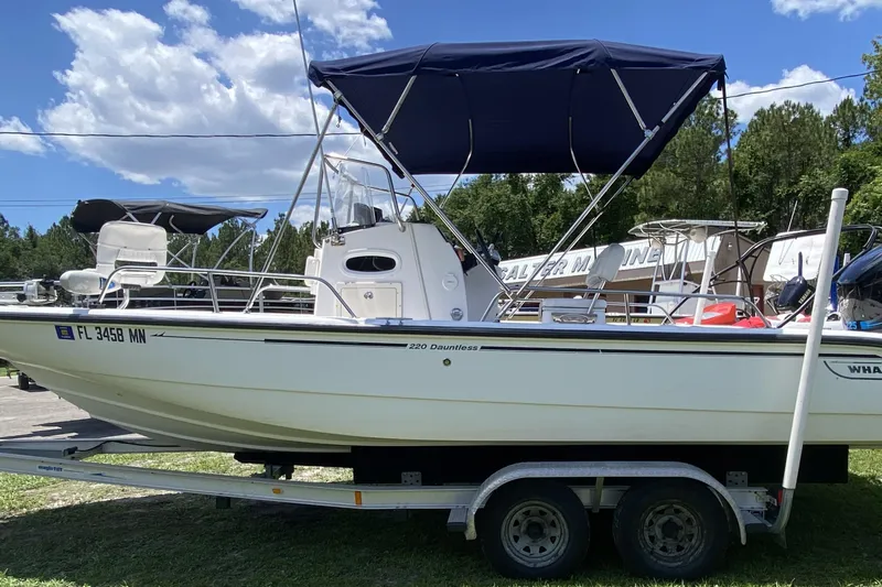 Slide: The Image of 2004 Boston Whaler 220 Dauntless boat on trailer with blue canopy, parked outdoors. - 6