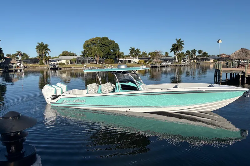 Slide: The Image of 2024 Nor-Tech 390 Sport Center Console boat on calm water, surrounded by palm trees. - 11