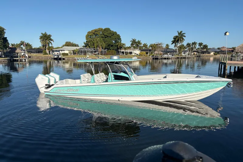 Slide: The Image of 2024 Nor-Tech 390 Sport Center Console boat on calm water, surrounded by palm trees. - 2