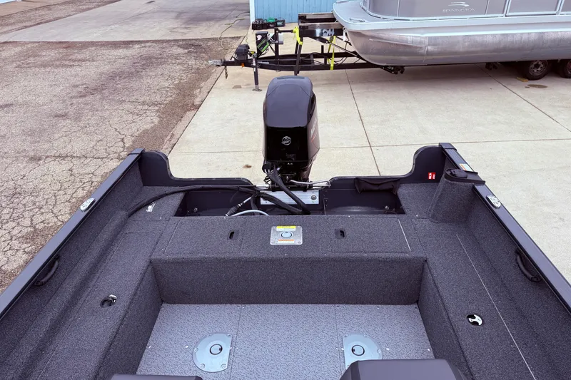 Slide: The Image of 2026 Lund 1650 Rebel XL SS boat interior with motor, parked on concrete. - 15