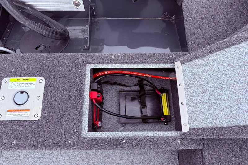 Slide: The Image of 2026 Lund 1650 Rebel XL SS boat battery compartment with wiring and caution label. - 18