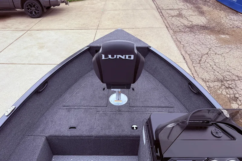 Slide: The Image of 2026 Lund 1650 Rebel XL SS boat interior with seating and console, parked on pavement. - 7