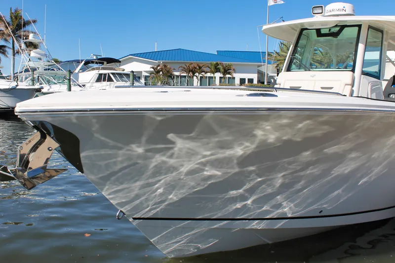 Slide: The Image of 2024 Sailfish 360 CC boat docked, reflecting sunlight on water, with marina background. - 39