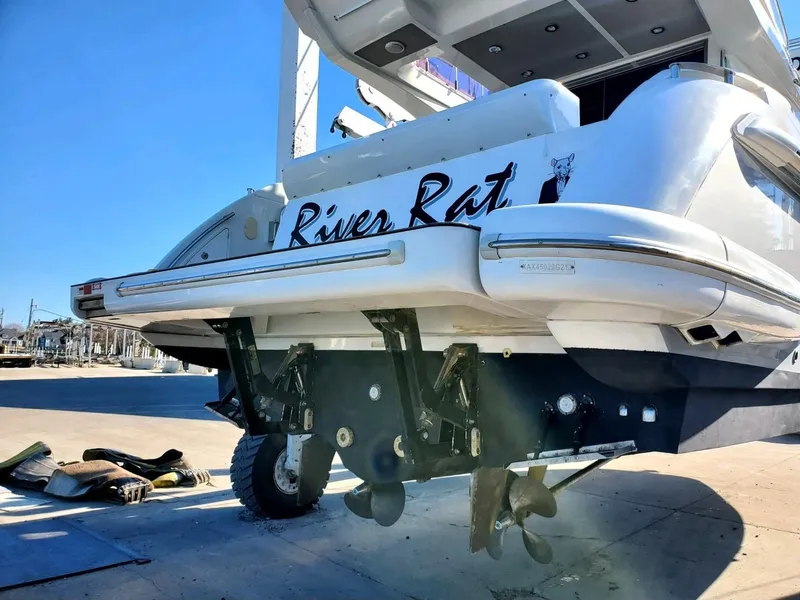 Slide: The Image of 2013 Azimut 45 Flybridge yacht, rear view, docked with visible propellers and "River Rat" name. - 4