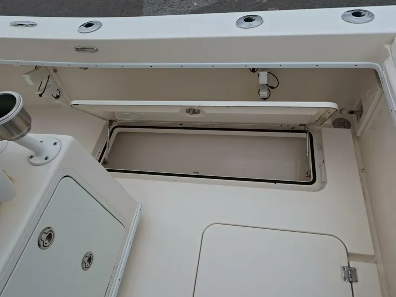 Slide: The Image of Open storage compartment on 2019 Young Boats 27, featuring white interior and cushioned lid. - 22
