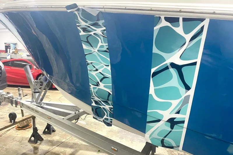 Slide: The Image of 2016 Edgewater 205CX Crossover boat with blue and patterned hull design on trailer. - 18