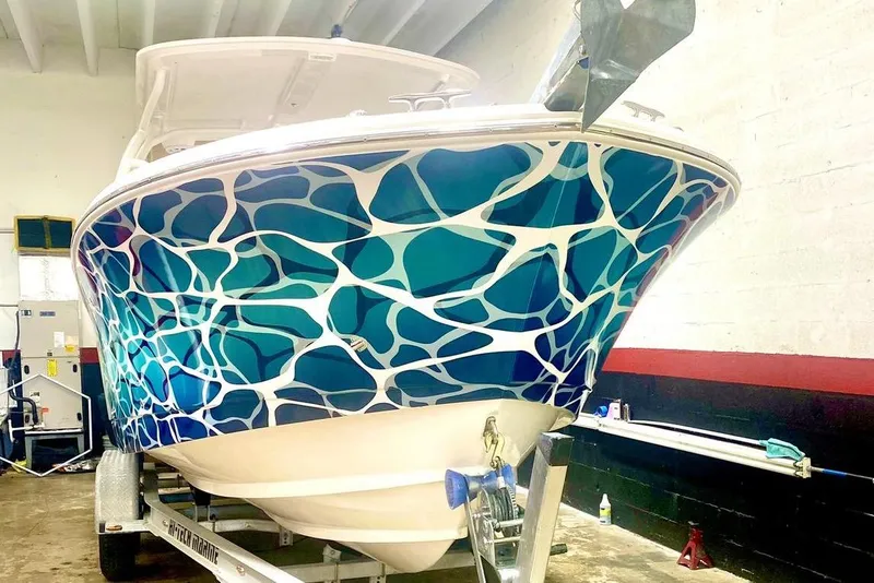 Slide: The Image of 2016 Edgewater 205CX Crossover boat with vibrant blue and white abstract design. - 6