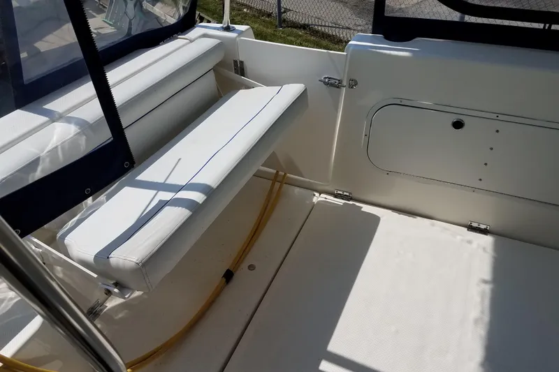 Slide: The Image of 2007 Bayliner Discovery 288 boat interior with white seating and storage compartment. - 10