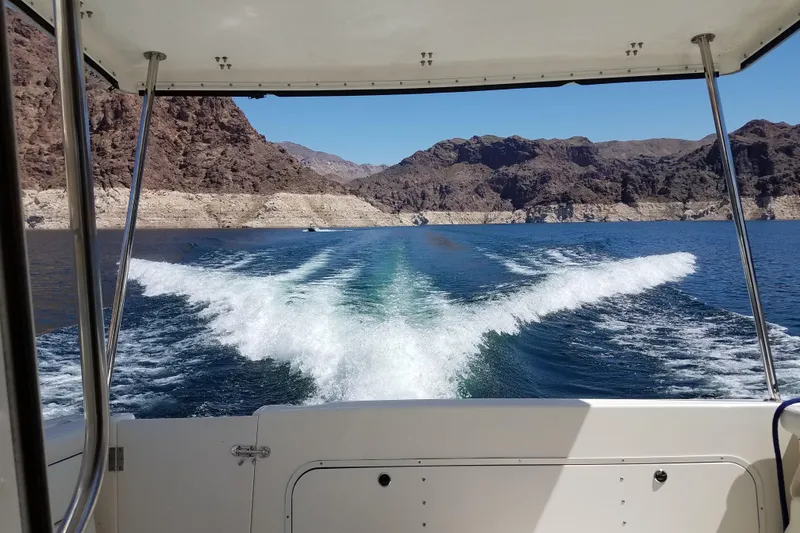 Slide: The Image of 2007 Bayliner Discovery 288 cruising on a lake with scenic rocky shoreline. - 13