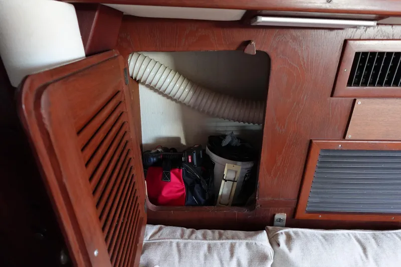 Slide: The Image of 1978 Morgan 382 sailboat interior storage compartment with wooden paneling and ventilation. - 31