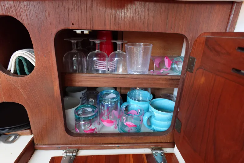 Slide: The Image of Wooden cabinet in a 1978 Morgan 382 yacht, storing glasses and mugs with flamingo designs. - 59