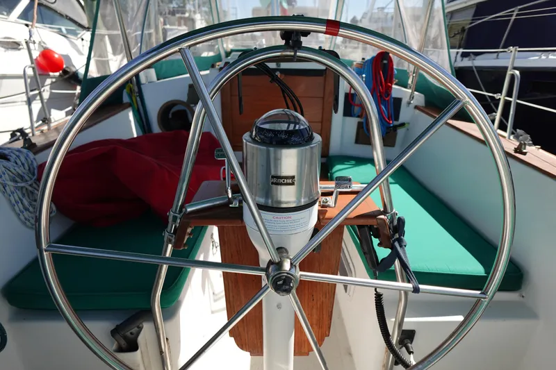 Slide: The Image of Steering wheel of a 1978 Morgan 382 sailboat with green seating and nautical equipment. - 86
