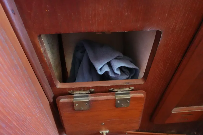 Slide: The Image of Wooden storage compartment in a 1978 Morgan 382 sailboat, containing a folded blue cloth. - 14