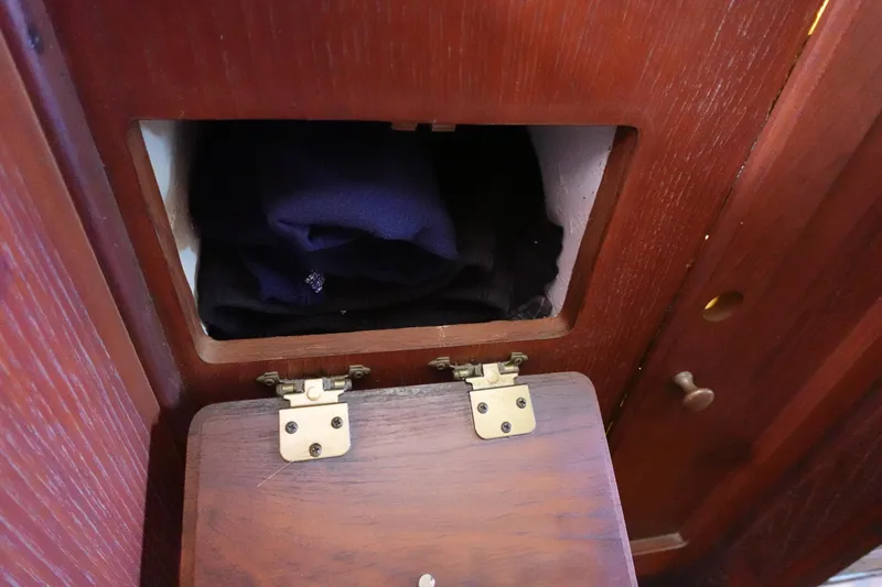 Slide: The Image of Wooden storage compartment in a 1978 Morgan 382 sailboat, containing folded clothes. - 15