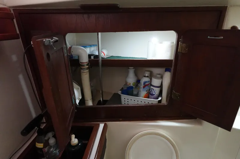 Slide: The Image of 1978 Morgan 382 sailboat bathroom cabinet with cleaning supplies and plumbing. - 22