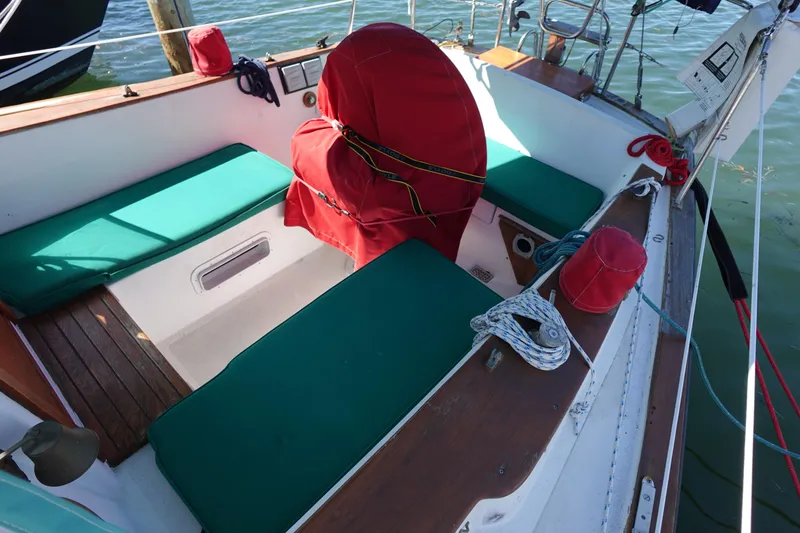 Slide: The Image of 1978 Morgan 382 sailboat cockpit with green cushions and red covers on a sunny day. - 5