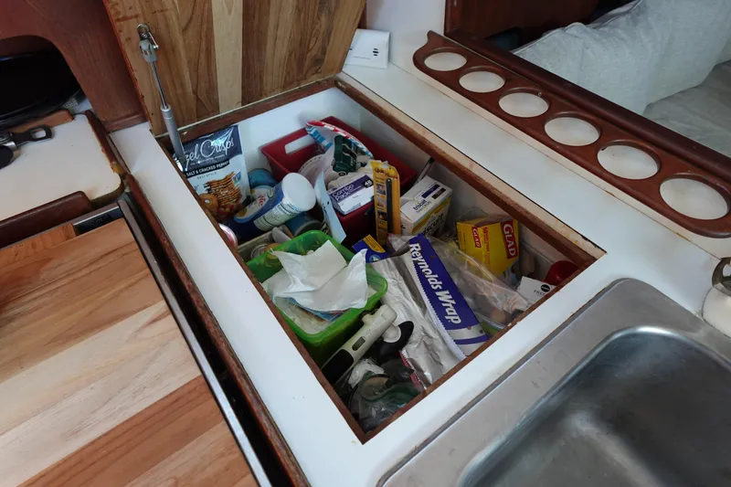 Slide: The Image of Storage compartment in a 1978 Morgan 382 sailboat galley, filled with kitchen supplies. - 57