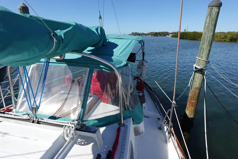 Slide: The Image of 1978 Morgan 382 sailboat docked, featuring teal canopy and clear windows. - 6