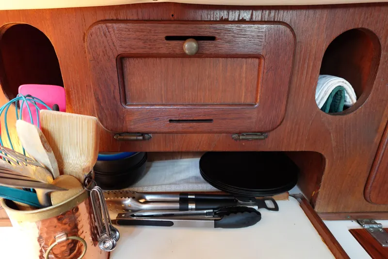 Slide: The Image of Wooden kitchen storage in a 1978 Morgan 382 sailboat with utensils and cookware. - 62