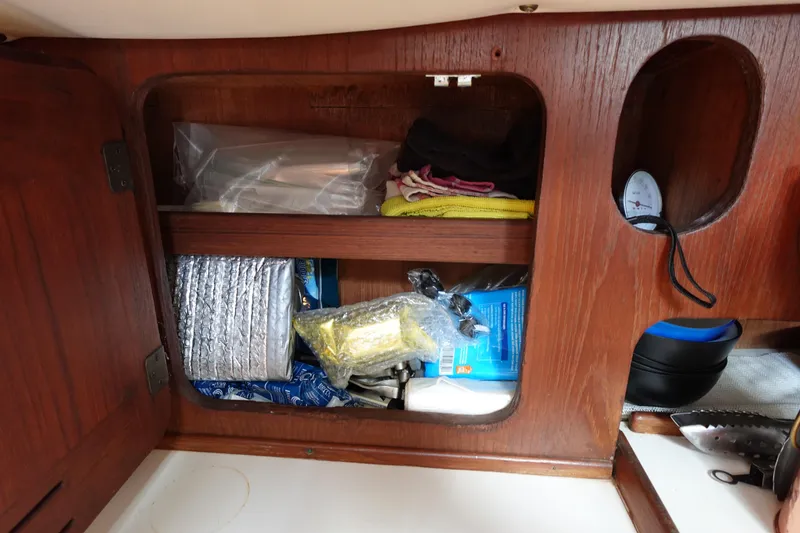 Slide: The Image of Storage compartment in a 1978 Morgan 382 sailboat with various supplies and equipment. - 63