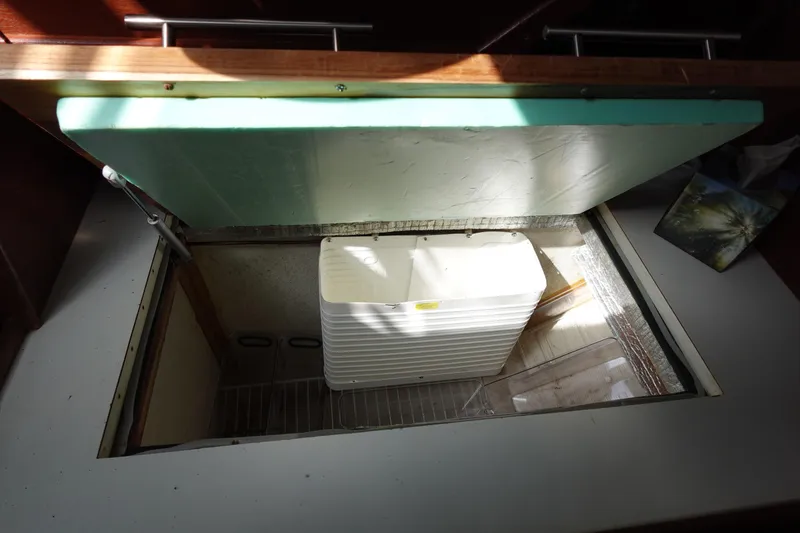 Slide: The Image of 1978 Morgan 382 yacht interior storage compartment with open lid and white container. - 66