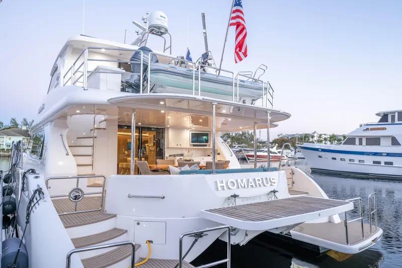 Slide: The Image of Luxurious 2021 Horizon yacht docked, featuring elegant outdoor seating and American flag. - 1