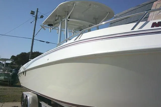 Slide: The Image of 1996 Fountain 31 Center Console boat with sleek white hull and T-top, docked outdoors. - 6