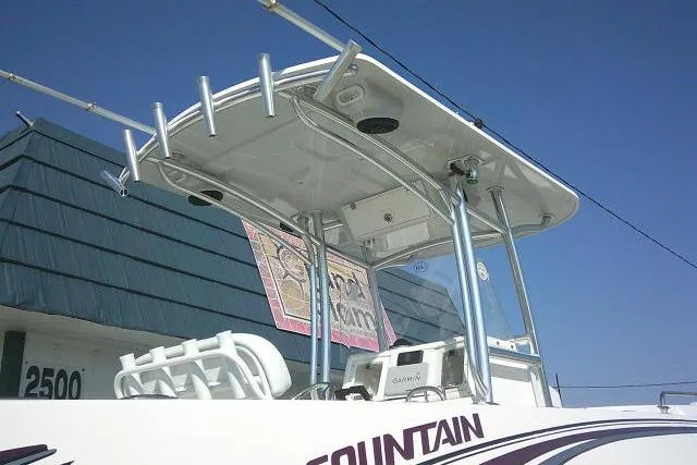 Slide: The Image of 1996 Fountain 31 Center Console boat with T-top and rod holders, docked under clear sky. - 9