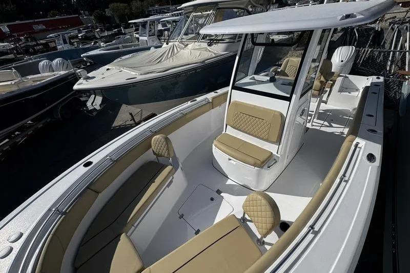 Slide: The Image of 2026 Sportsman Open 252 Center Console boat with tan seating, docked among other boats. - 13