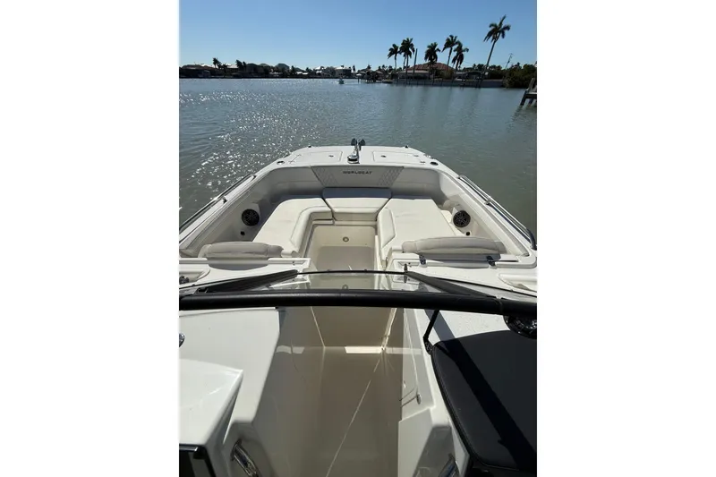 Slide: The Image of 2025 World Cat 260 DC-X boat interior with seating, on calm water, palm trees in background. - 3