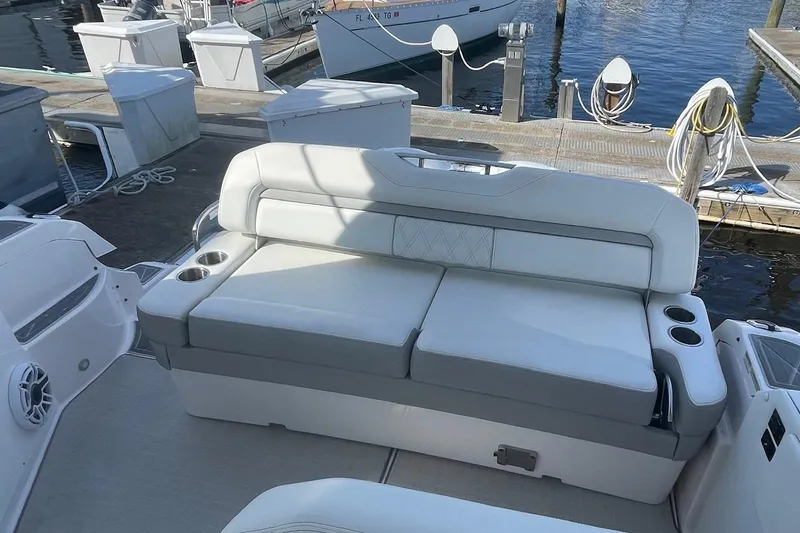 Slide: The Image of 2021 Regal 33 XO boat interior with white cushioned seating and cup holders at a marina. - 10