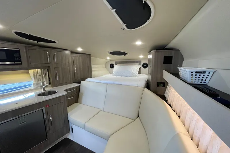 Slide: The Image of 2021 Regal 33 XO boat interior with modern kitchen, seating, and cozy sleeping area. - 17