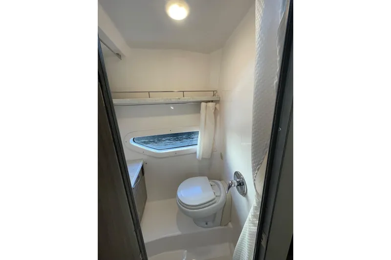 Slide: The Image of 2021 Regal 33 XO boat bathroom with toilet, window, and shower curtain. - 22