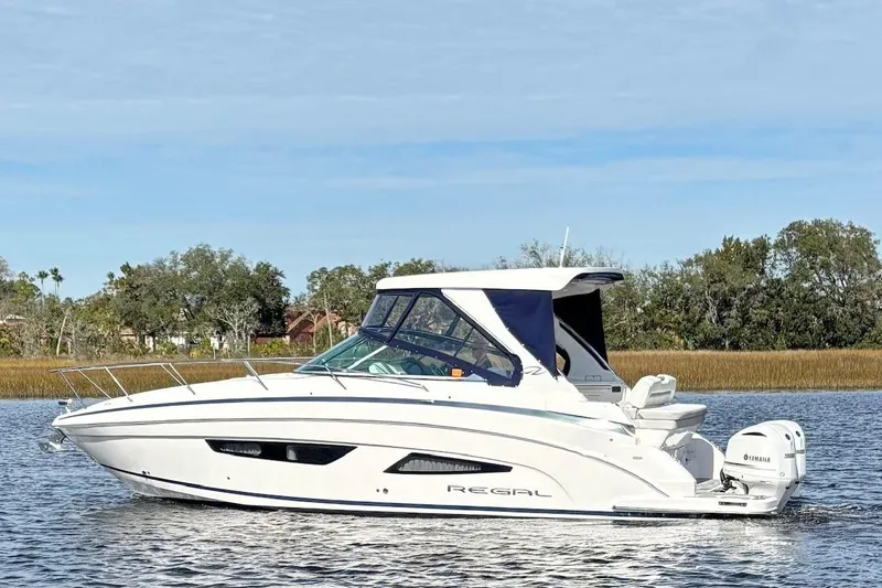 Slide: The Image of 2021 Regal 33 XO boat cruising on a calm lake with scenic background. - 3