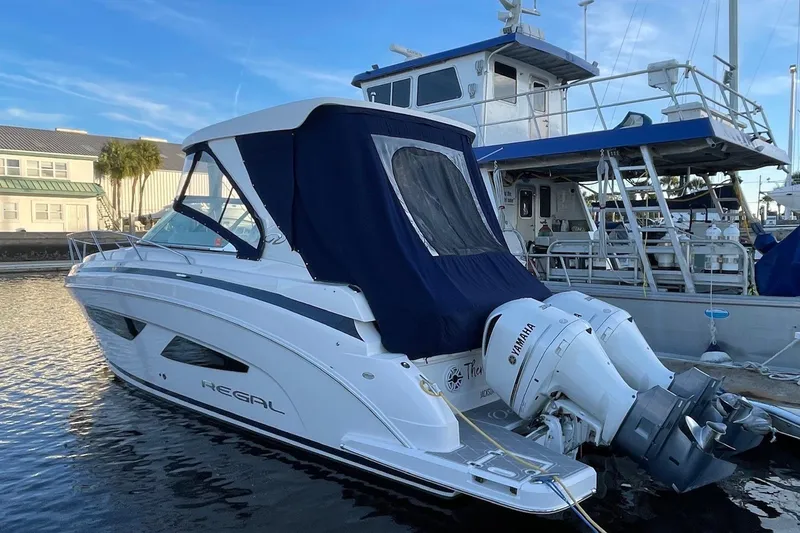 Slide: The Image of 2021 Regal 33 XO boat docked with Yamaha engines, featuring a blue canopy. - 9