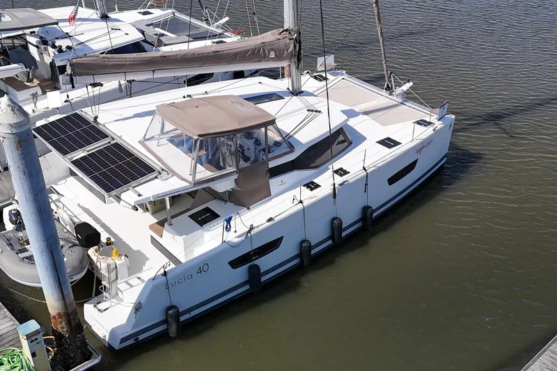 Slide: The Image of 2016 Fountaine Pajot Lucia 40 catamaran docked, featuring solar panels and spacious deck. - 102