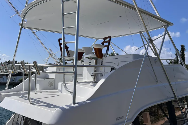 Slide: The Image of 2001 Hatteras 65 Convertible yacht with elevated flybridge and seating, under clear blue sky. - 11