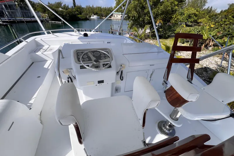 Slide: The Image of 2001 Hatteras 65 Convertible yacht helm with white seating and steering wheel. - 14
