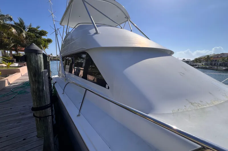 Slide: The Image of 2001 Hatteras 65 Convertible yacht docked by a sunny waterfront. - 2