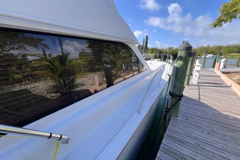 Slide: The Image of 2001 Hatteras 65 Convertible yacht docked by a wooden pier under a clear blue sky. - 21