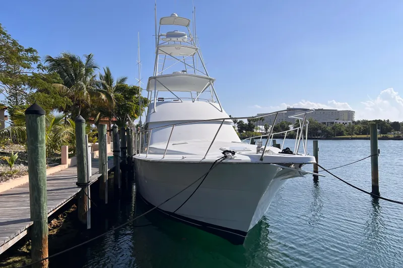 Slide: The Image of 2001 Hatteras 65 Convertible yacht docked by palm trees and clear water. - 3