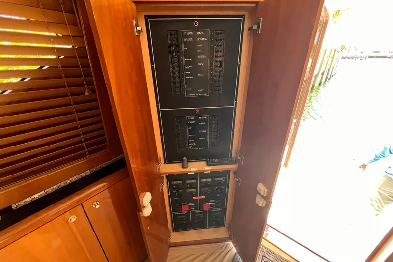 Slide: The Image of Electrical panel inside 2001 Hatteras 65 Convertible yacht, featuring wooden cabinetry and control switches. - 36