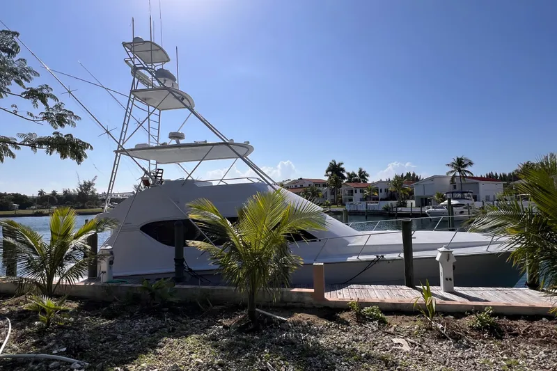 Slide: The Image of 2001 Hatteras 65 Convertible yacht docked by palm trees under clear blue sky. - 4
