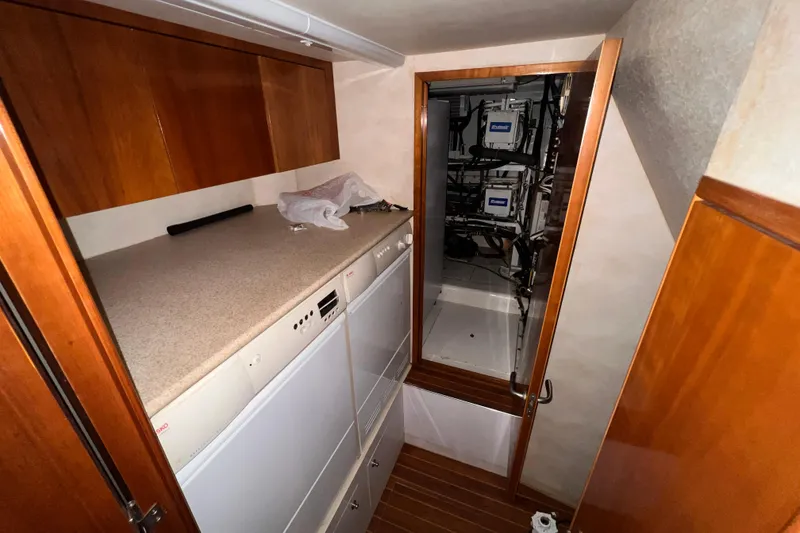 Slide: The Image of 2001 Hatteras 65 Convertible yacht interior with wooden cabinets and laundry appliances. - 57